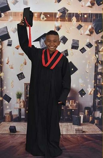 Graduando con toga negra levantando el birrete
